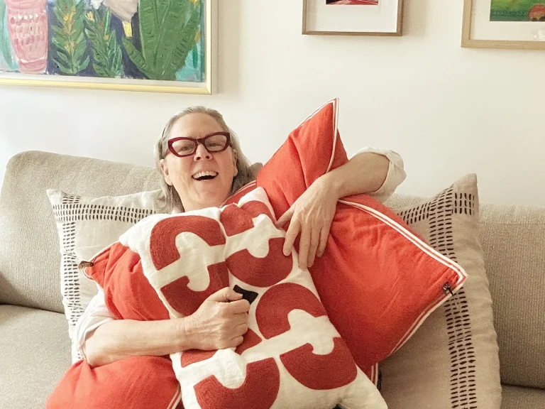 woman on sofa, holding colourful pillows, cozy room