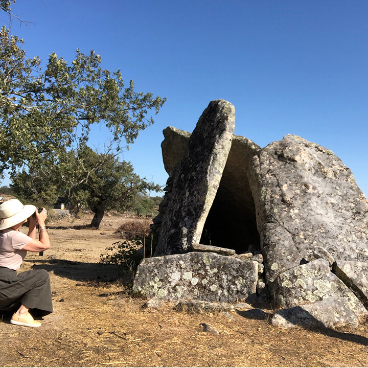 woman photographing megalithic stone burial in Portugal