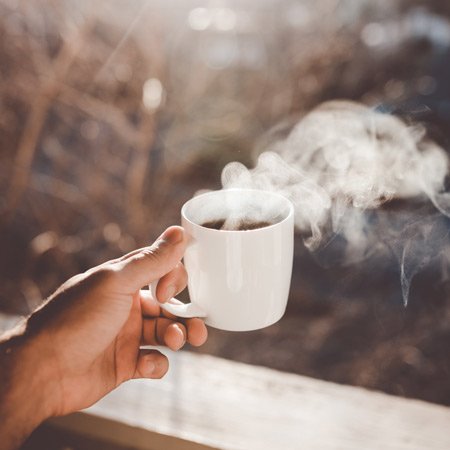 hand holding a mug and steam coming out of it