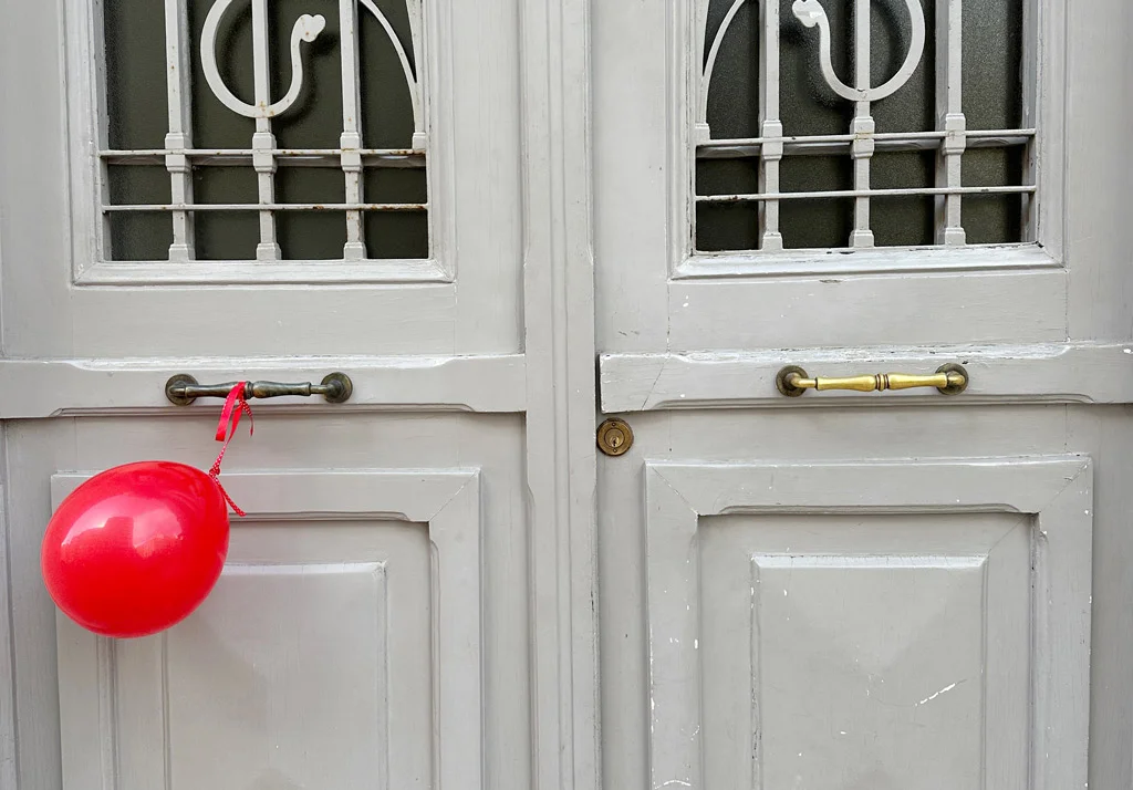 red balloon hanging on a gray double door
