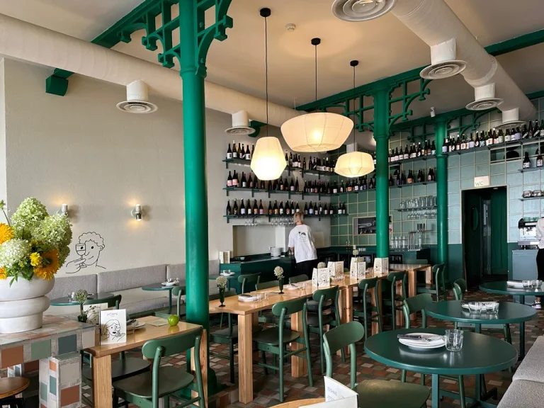 interior of Pomme Eatery restaurant, Green columns, industrial feel, wood tables and chairs