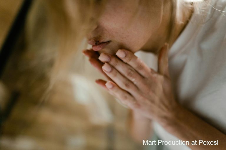 photo of blurred female face hands in prayer position in focus. Feeling pain and pain mangagement