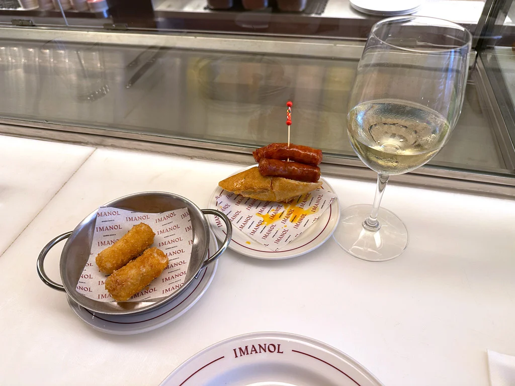 Tapas at Imanol croquetas and sausage plate, a glass of white wine