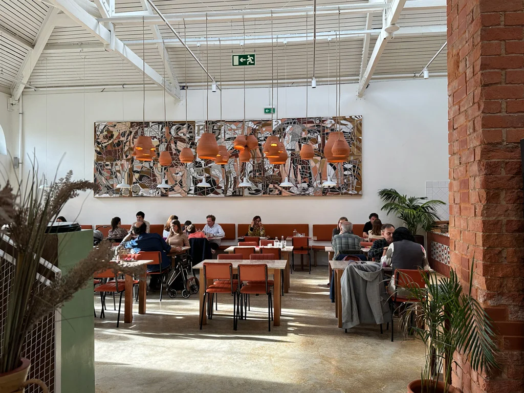Reitorio restaurant in Beato. Painting on the wall. Industrial building. Earthy colors. Plants on the sides. White wall.