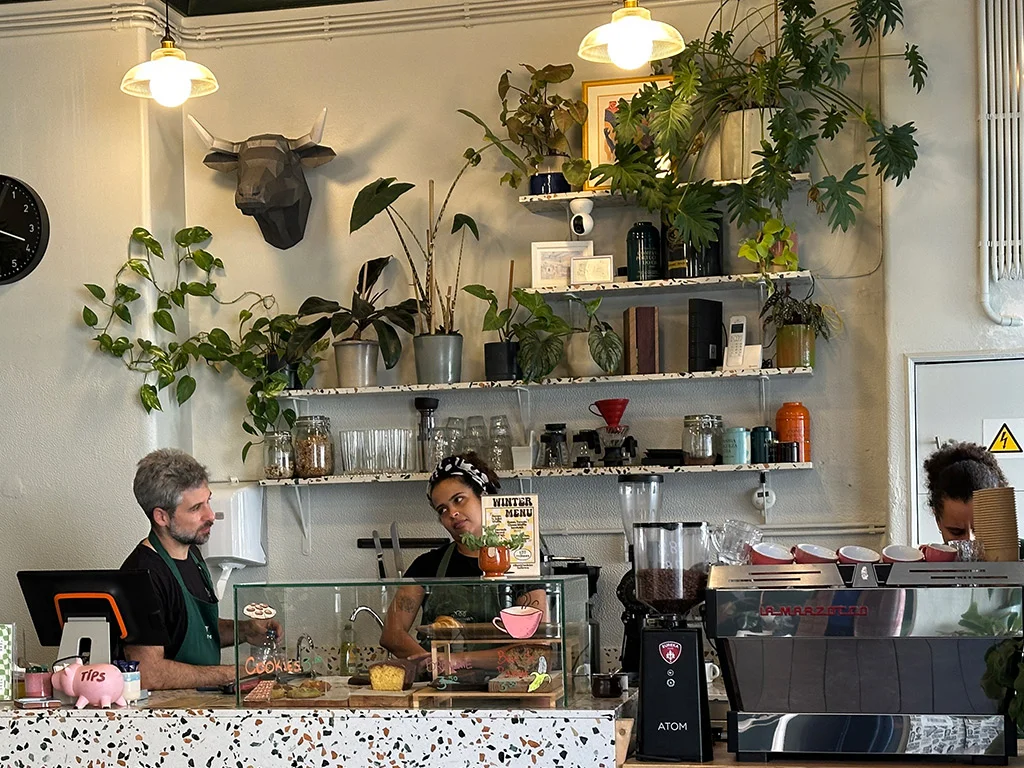 inside Milkees cafe lisbon, many plants people back of counter