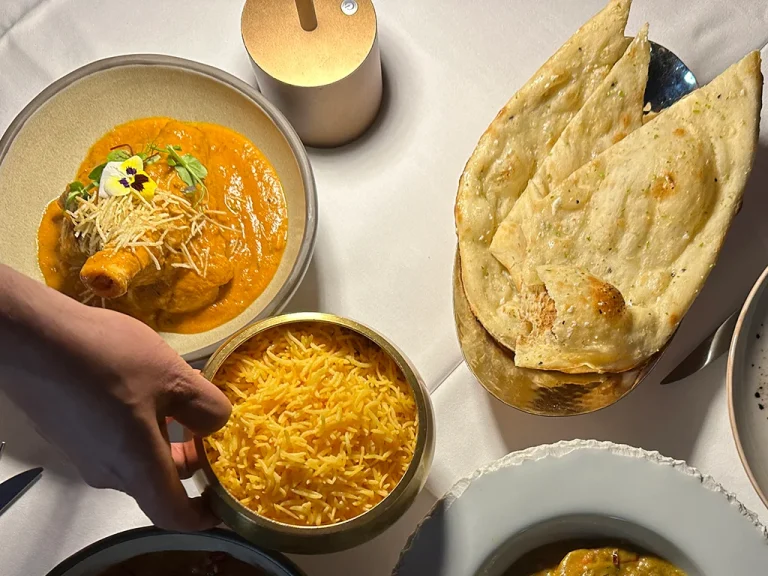 hand holding dish of Saffron rice , Naan bread on another dish, The Oven