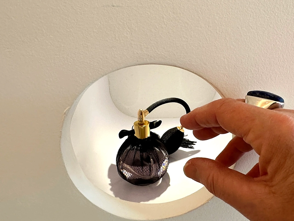 perfume hand about to hold a black perfume bottle, joy spot