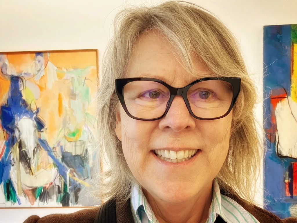 photo of woman wearing glasses, in front of paintings, solo travel after 65