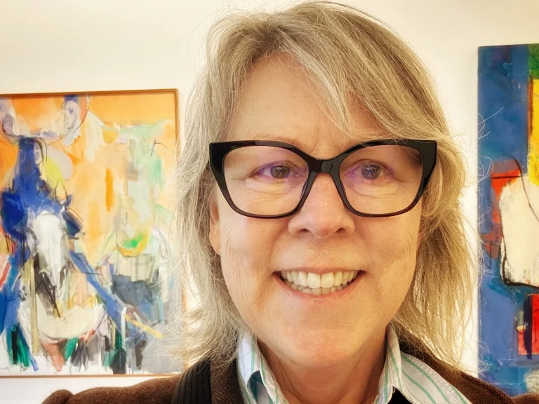 photo of woman wearing glasses, in front of paintings, solo travel after 65